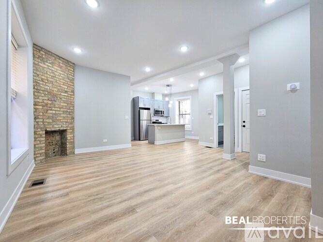 A spacious room with a brick fireplace and wooden flooring.