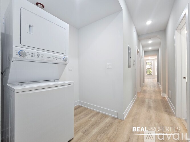 A white oven is in a kitchen with white walls and wood flooring.