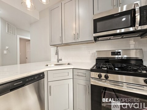 A modern kitchen with a stove, sink, and cabinets.