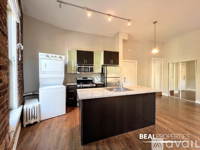 A spacious room with wooden floors and brick walls.