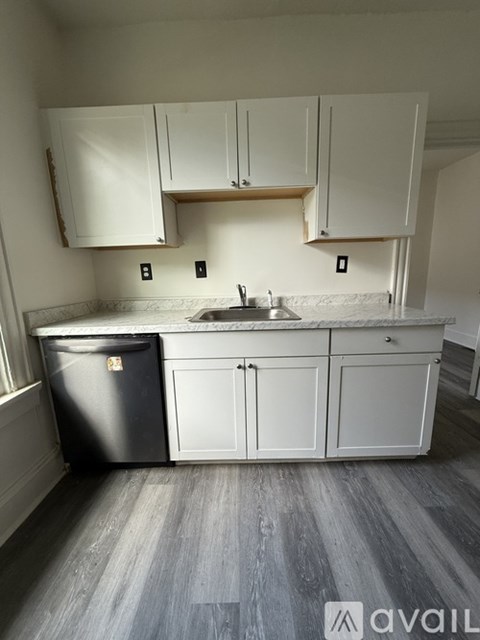 A kitchen with white cabinets and a black fridge.