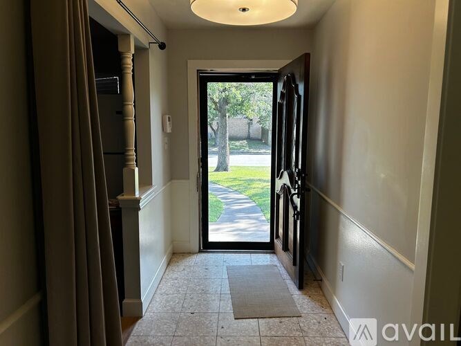 A hallway with a tiled floor and a sliding glass door leading to a green outdoor area.