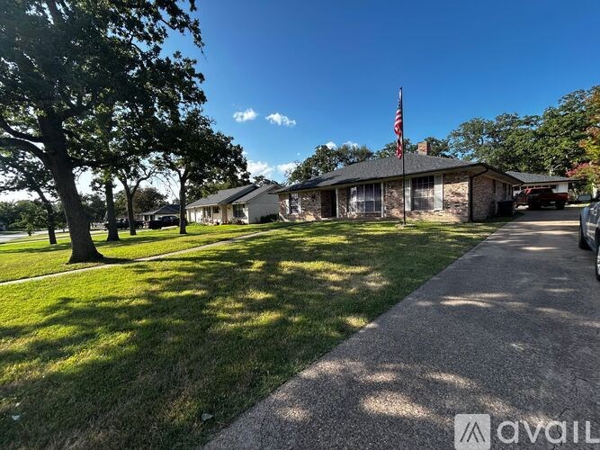 A house with a flag on the roof and a driveway in front.