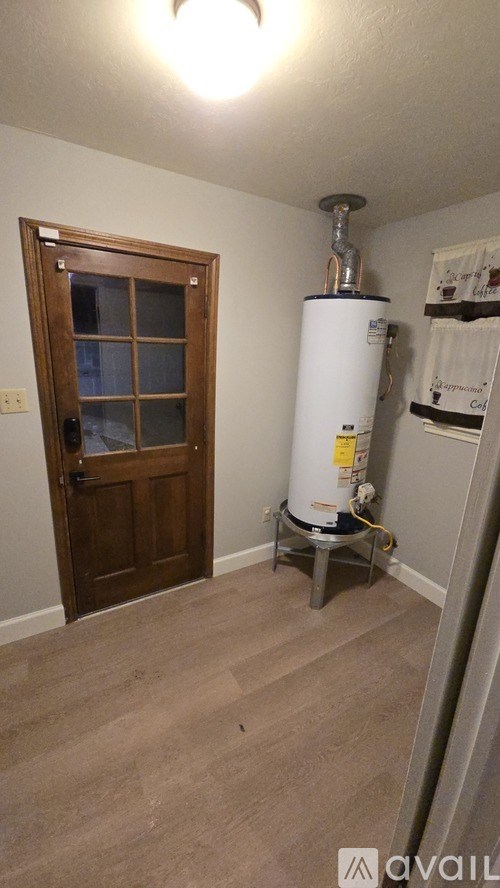 A room with a water heater and a door.