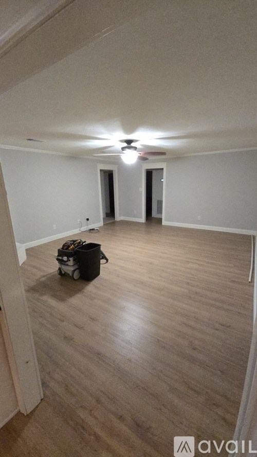 A room with a ceiling fan and a black bag on the floor.