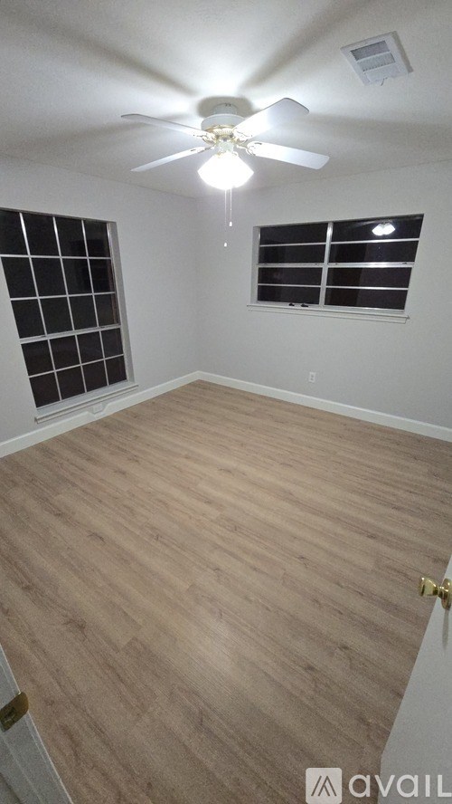 A room with a ceiling fan and wooden flooring.