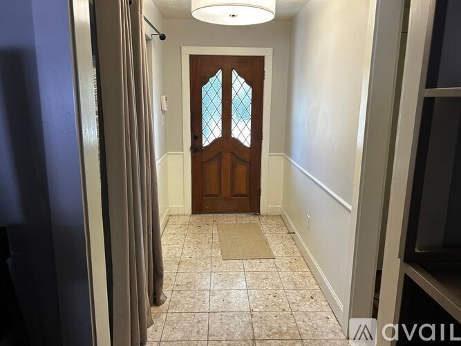A hallway with a wooden door and a tiled floor.