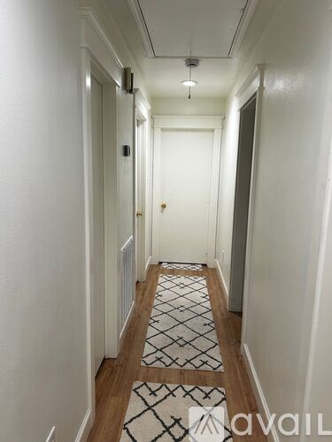 A long hallway with a rug on the floor and a door at the end.