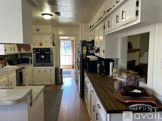 A kitchen with white cabinets and a wooden counter top.
