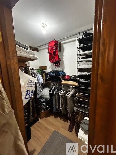 A room with a lot of clothes hanging up and a red bag hanging on the wall.