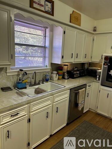 A kitchen with white cabinets and a window above the sink.