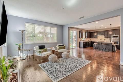 A living room with a grey rug and a wooden floor.