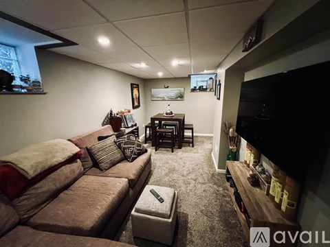 A living room with a brown couch and a flat screen TV mounted on the wall.