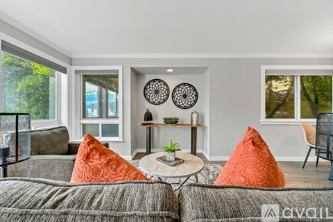 A living room with grey couches and orange pillows.