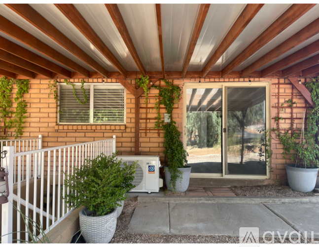 A patio area with a white railing, a white air conditioning unit, and a white door.
