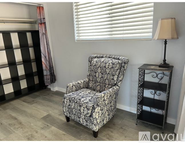A chair with a floral pattern sits next to a lamp on a table.
