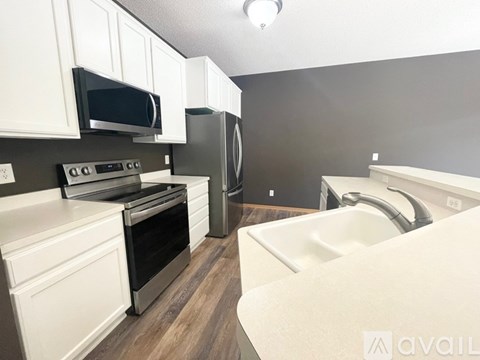 A kitchen with white cabinets and a stainless steel refrigerator.