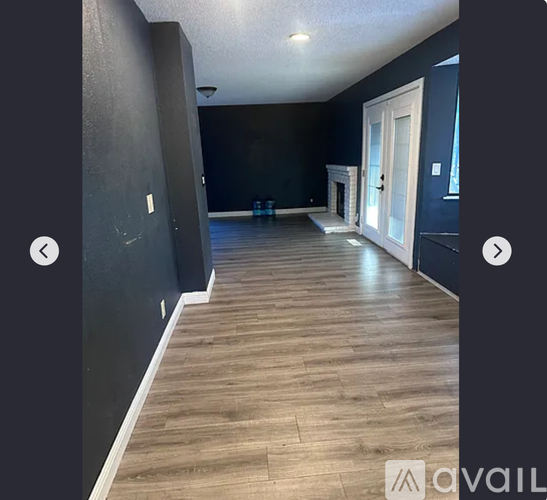 A room with wooden flooring and dark walls.