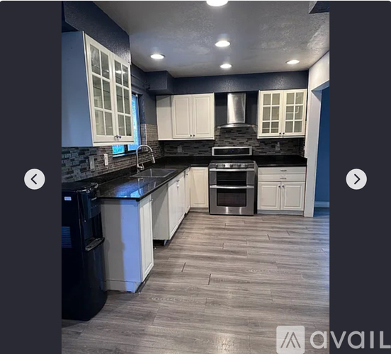 A modern kitchen with a black countertop and stainless steel appliances.