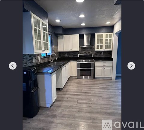 A modern kitchen with a black countertop and stainless steel appliances.