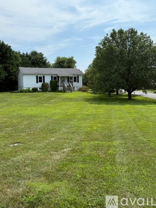 A white house with a green lawn in front of it.