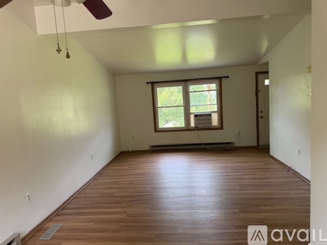 A room with wooden floors and a window with blinds.