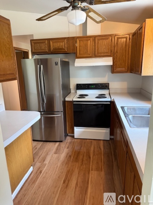 A kitchen with wooden cabinets and a stainless steel refrigerator.