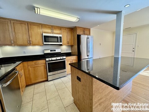 A kitchen with wooden cabinets and black countertops.