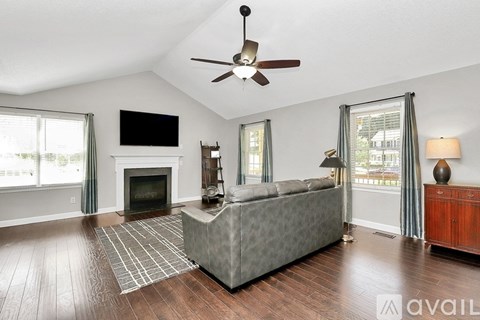 A living room with a grey sofa, a fireplace, and a television on the wall.