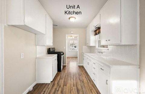 A kitchen with white cabinets and a wooden floor.