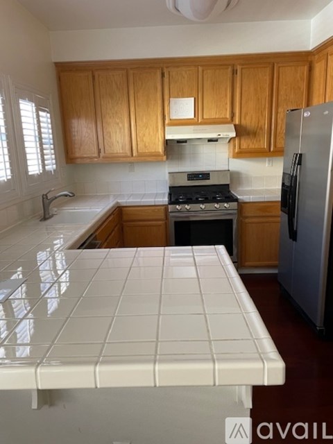 A kitchen with wooden cabinets and a white tile counter.