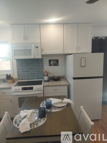 A kitchen with white cabinets and a wooden table.