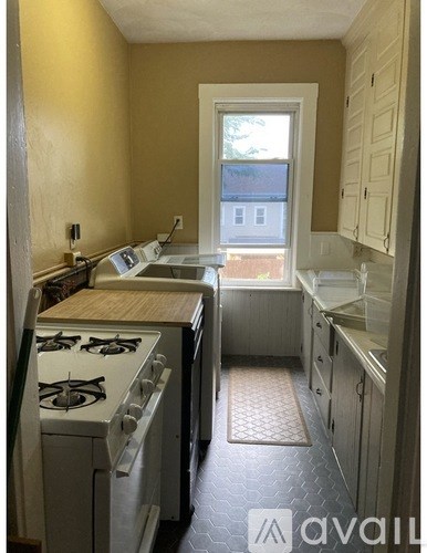 A kitchen with a stove top oven and a window.