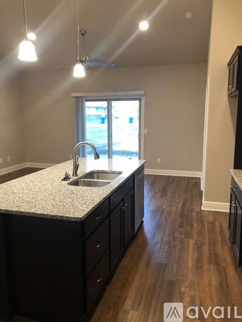 A kitchen with dark wood cabinets and a granite countertop.
