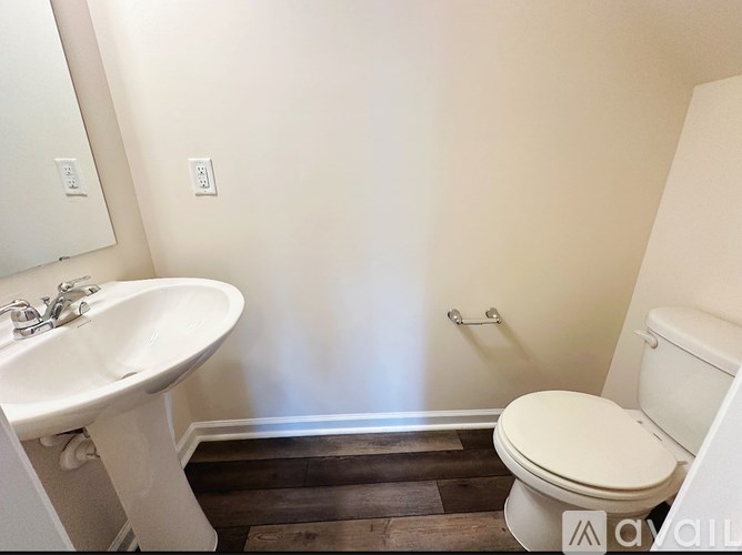 A white toilet sits next to a white sink in a small bathroom.
