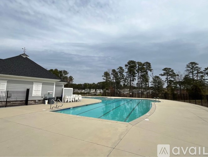 A swimming pool in a backyard with a house and trees in the background.