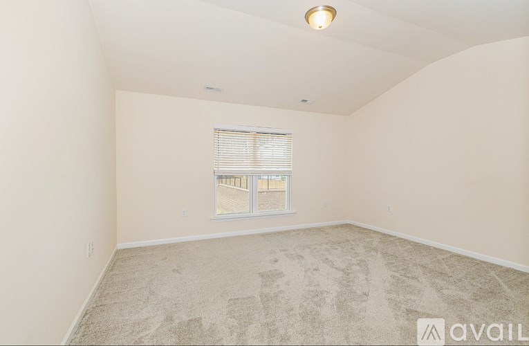 A room with a carpeted floor and a window with blinds.