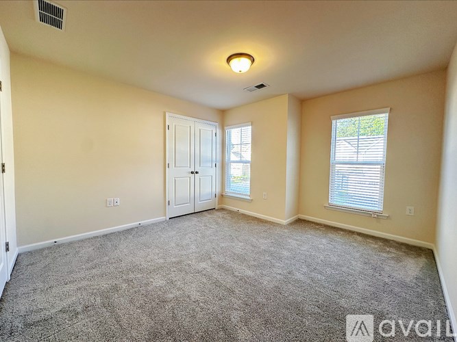 A carpeted room with a door and a window.