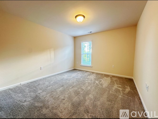 A room with a carpeted floor and a window with blinds.