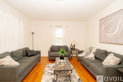 A living room with two grey couches, a coffee table, and a large abstract painting on the wall.