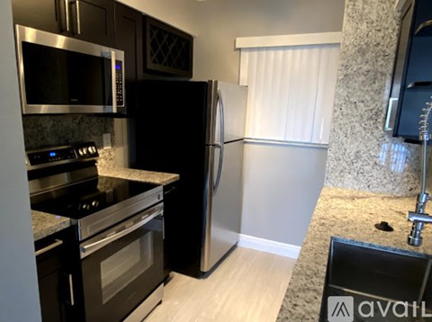 A kitchen with a black refrigerator and stove top oven.