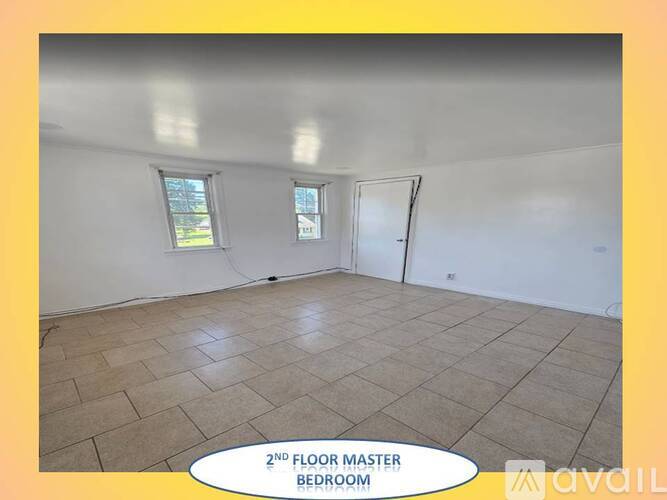 A spacious second floor master bedroom with tiled flooring and two windows.