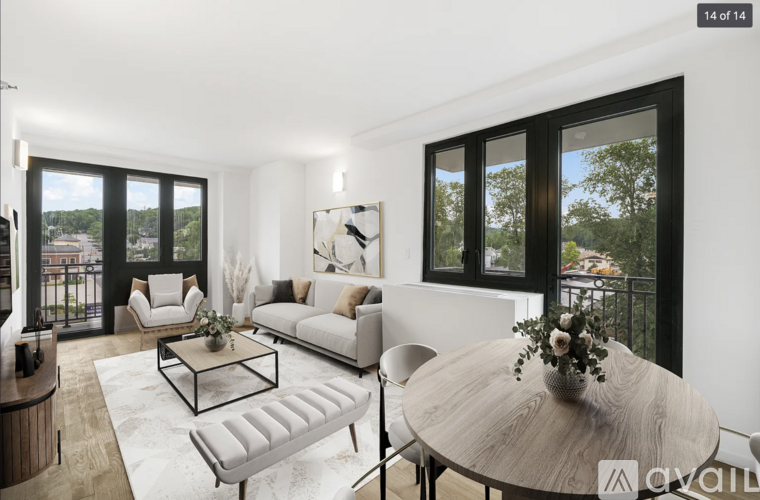 A modern living room with a white sofa, a coffee table, and a round table with a vase of flowers on it.