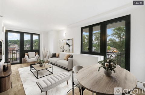 A modern living room with a white sofa, a coffee table, and a round table with a vase of flowers on it.