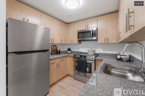 A kitchen with a stainless steel refrigerator, microwave, oven, and sink.
