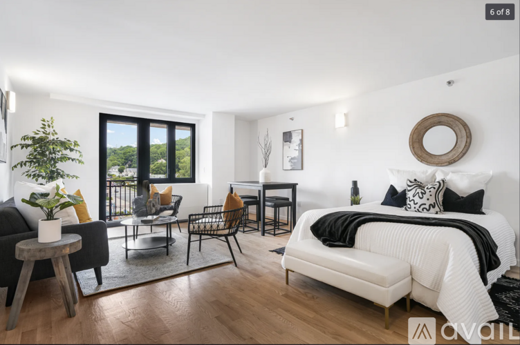 A modern bedroom with a large bed and a balcony with a view of the trees.