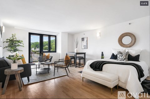 A modern bedroom with a large bed and a balcony with a view of the trees.