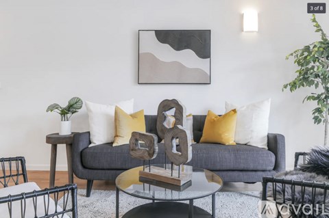 A grey couch with yellow and white pillows is the centerpiece of a modern living room.