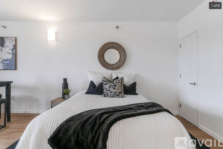 A bedroom with a white bed and a black and white pillow.
