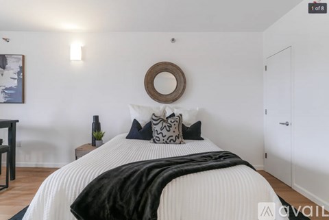 A bedroom with a white bed and a black and white pillow.